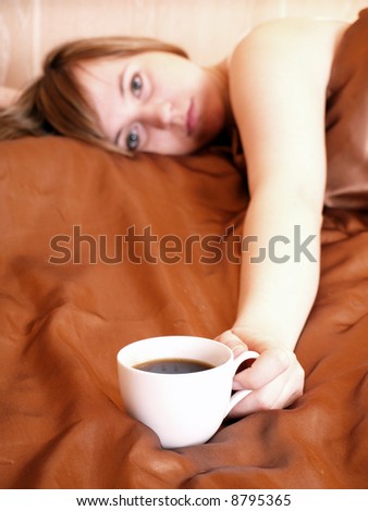 Young woman relaxing in the bedroom with coffee