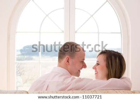 Couple sitting on the sofa and smiling/ Window on the world / freedom / new time