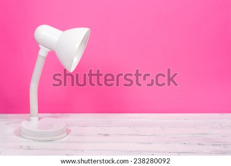 White lamp on white wood desk on pink background
