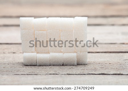 The sugar pressed in cubes put by a pyramid on a wooden table from old boards.