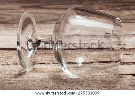 Cognac  glass the lying on one side on a wooden table from old boards, empty glass for alcoholic beverages on one side.
