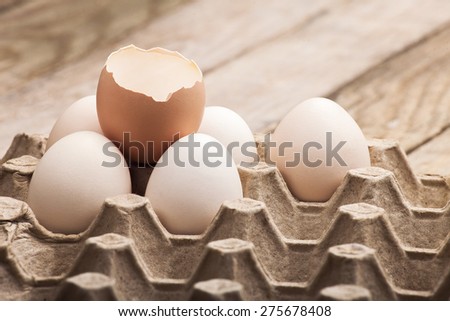 The eggs which are laid out in a paper tray on a wooden table from old boards with the split egg from above, nobody.