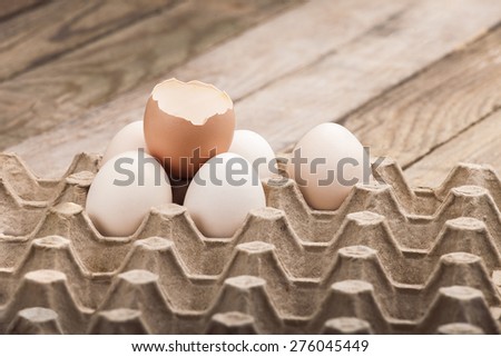 Eggs chicken, laid out in a tray on a heap with one split egg, on a wooden background of nobody.