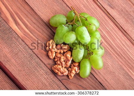 grapes of green color and walnut on a wooden table from boards.