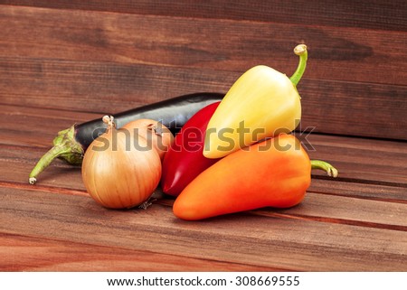 Vegetables on a wooden table from brown boards, vegetarian healthy food, paprika, onions, an eggplant.