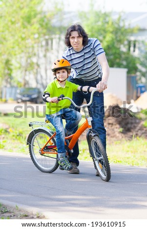 father teaches son how to ride a Bicycle