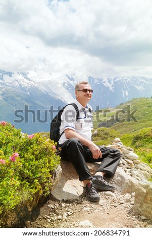 Fifty years  tourists  sitting on a rock in blossoming rhododendrons and admiring the mountain landscapes,