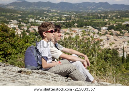 The boy and man sit on top of hill and look on rural town