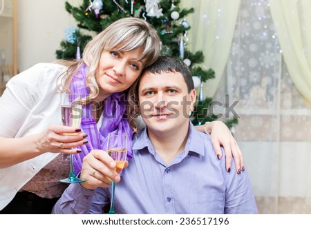a couple of middle age with glasses of champagne at the Christmas tree