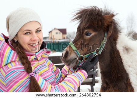 Young woman and miniature horse in winter park