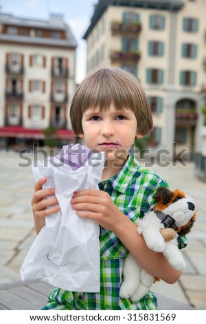 The six years boy eats french merengue on town square