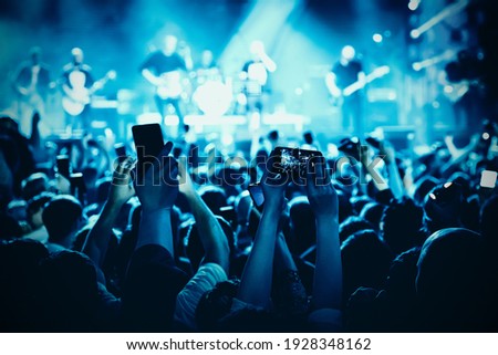 A lot of hands with the smartphone turned on to record or take pictures during the live concert