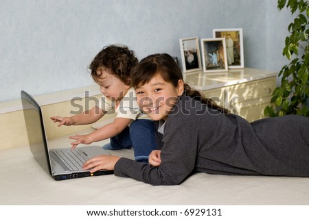 The elder sister and the junior brother play on a computer.