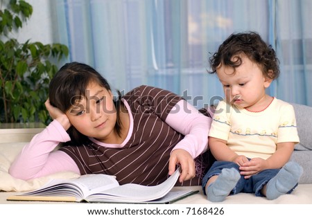The elder sister reads the book to the brother.