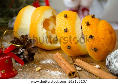 Orange peel, cinnamon stick, pine cone and spices among christmas decorations on wooden table