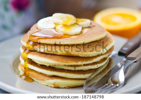 Stack of delicious pancakes with banana and maple syrup