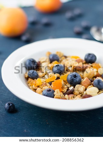 Healthy homemade granola with blueberry and dried apricot in a bowl on a wooden table