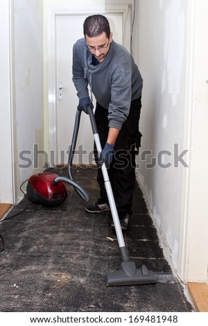 Workman vacuuming a passage during renovations after removing the old floor tiles