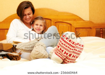 Mom and daughter lying on the bed in knitted socks