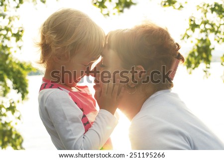 cute little daughter gently stroking her mother\'s face. mother and daughter looking at each other\'s eyes