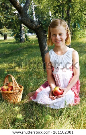 Little girl collects the apples in the apple orchard