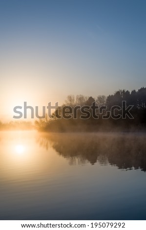 The sun rises over a calm lake.