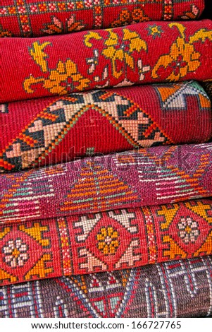 Pile of north african rugs in red, orange & brown shades, Morocco.