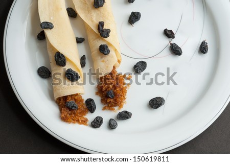 Rolled Pancakes with grated coconut filling, decorated with colorful sweet gems and dried grapes