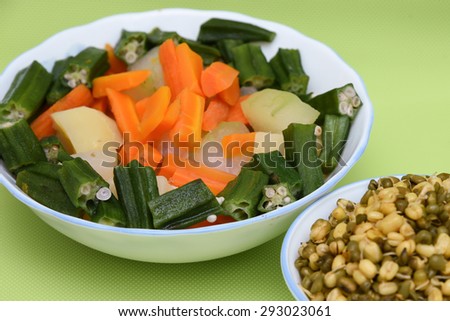 fresh vegetables carrot ladies finger potatoes cut up slices for making sambar India in bowls and sprouted seeds of green gram isolated on green