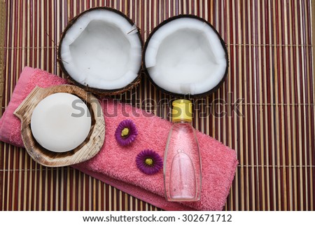 Fresh coconut cut open in half with extra clear and pure coconut oil. tropical Spa beauty exotic tropical flowers towels soap setting. Wellness & spa massage alternative treatment with coconut oil