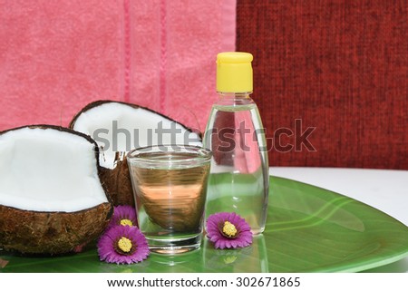 Fresh coconut cut open in half with extra clear and pure coconut oil. tropical Spa beauty exotic tropical flowers towels soap setting. Wellness & spa alternative treatment with coconut oil