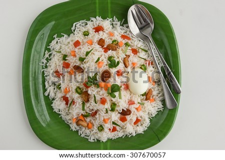 Close up of Delicious Indian Pulav / pilaf / fried rice in green plate Boiled egg cut open in half, fork spoon made of Basmati  rice, vegetable, nuts or meat,chicken.garnished with herbs