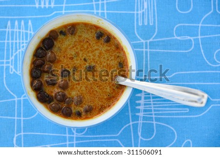Delicious Black Gram & Black Lentils Curry in a white bowl on blue mat background .sidedish for appam, puttu, chappathi, puri, battoora ,Paratha. kadala curry in Kerala, spicy Chana masala North India