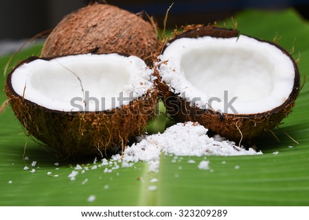 Fresh coconut cut open in half isolated on green banana leaf background Kerala India. Grated coconut top view. for cooking, frying, seasoning sambar, chutney.desiccated coconut oil