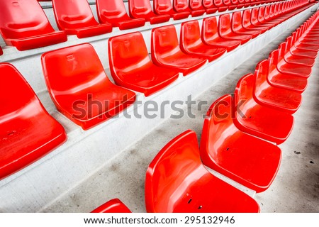Red stadium seats on concrete stands inside a sports stadium