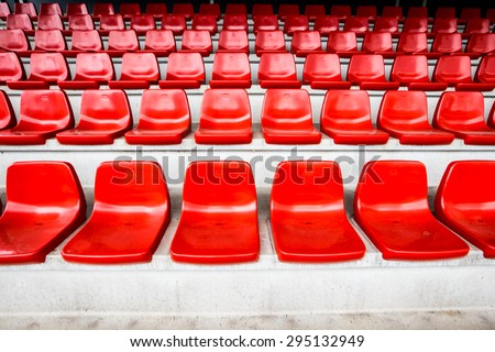 Red stadium seats on concrete stands inside a sports stadium