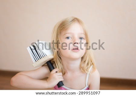 Little girl sitting with a paint brush. Apartment repair. Wallpapering. Stock Photo