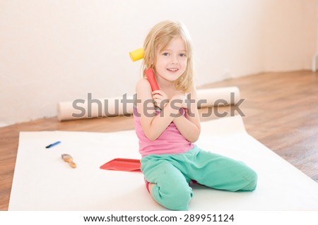 Little girl sitting with tools in his hands. Apartment repair. Wallpapering. Stock Photo
