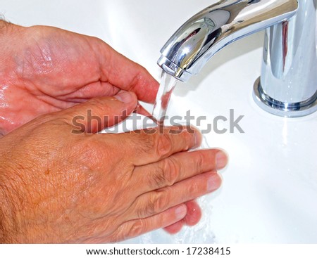 Elderly man washes his hands in bathroom