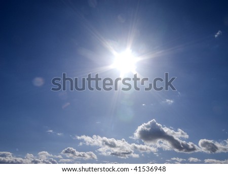 Sun flare from sun in cloudy blue sky