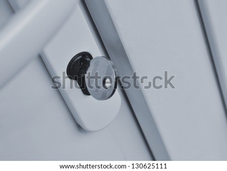 Closeup of key in front door lock (toned blue).