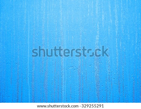 Water drops on steamed up window overlaid with blue color