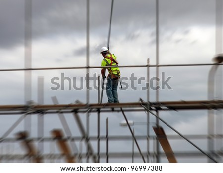 Construction worker assembling scaffolding on building site with zoom effect.