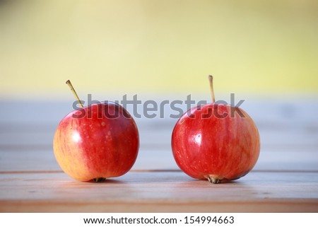 Two wild apples on a wooden table top with gap between them