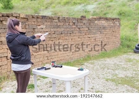 Civilian girl is practicing with her 9mm gun in a shooting range for improving her self-defense technique with gun