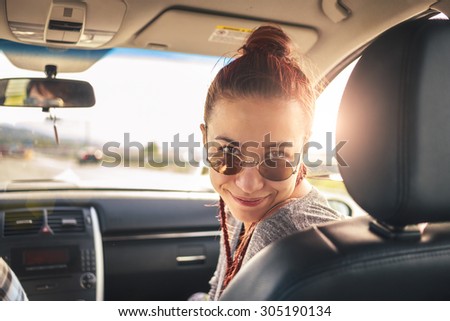 Girl in vehicle with sun shining is looking at the camera