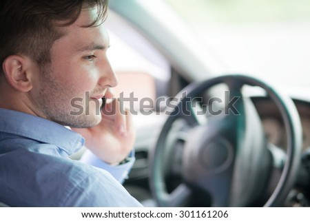 young businessman in his car at the wheel talking on a mobile phone