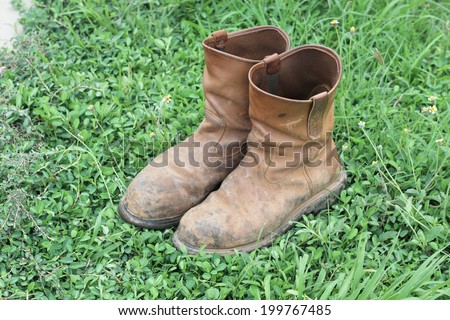 Old brown work boots on green grass