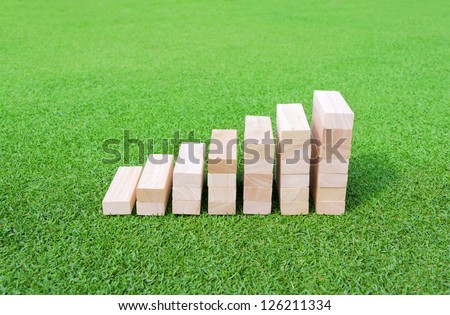 Wood Graph on the green Field for success and achievement concept.