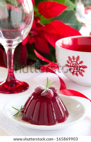 A red berries jelly on a plate with christmas tree in the background, selective focus